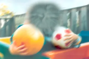 Age Related Macular Degeneration depiction. A child holding 2 footballs, but the image is severely blurred and has a very distorted centre.