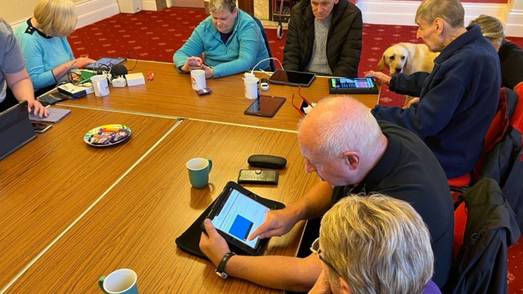 A group of service users learning about technology equipment.
