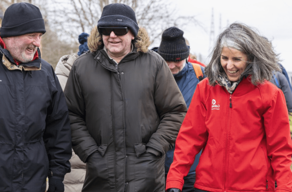 A group of people walking together outdoors, smiling and chatting as they enjoy the fresh air and each other's company.