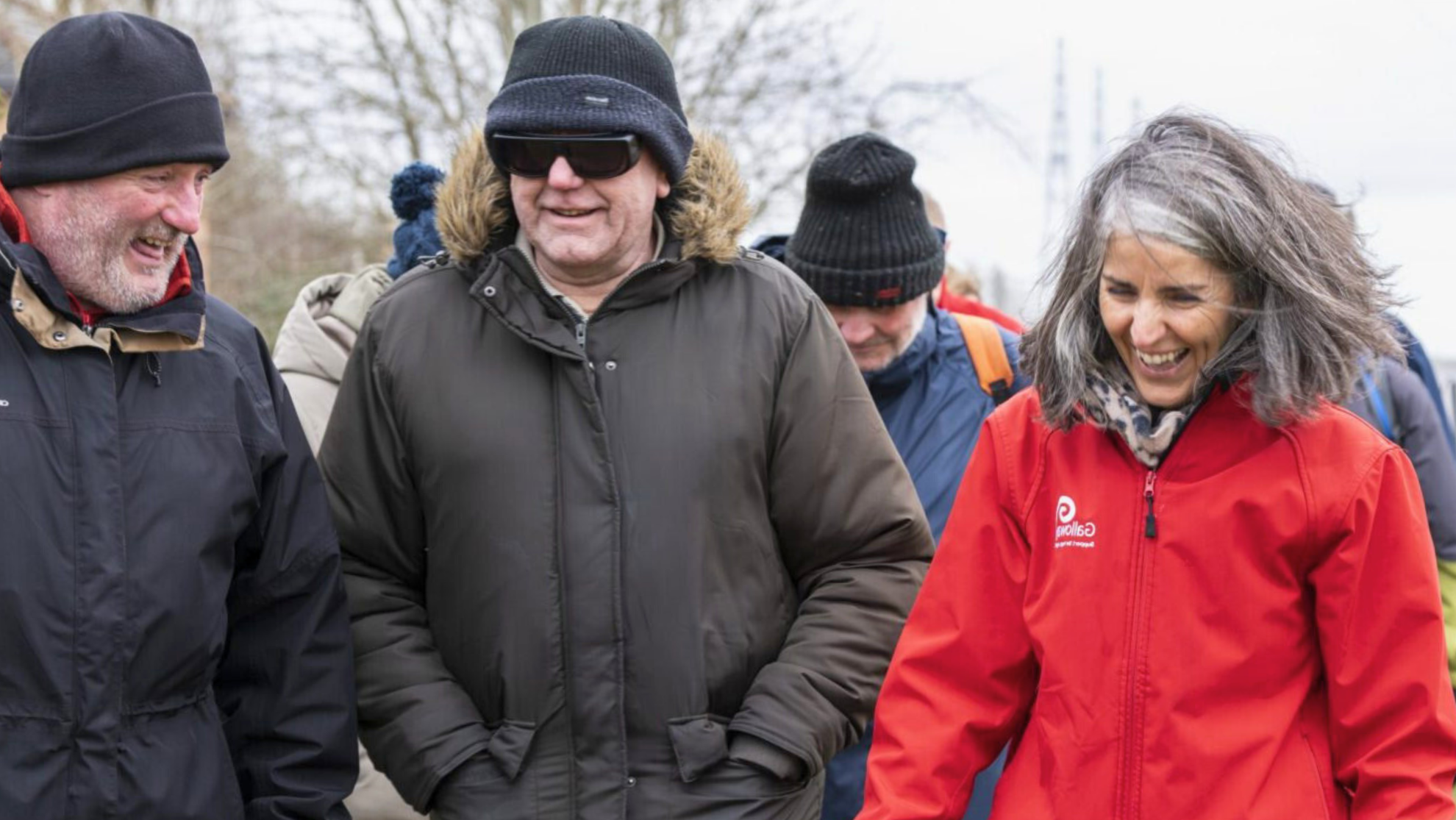 Image of 3 people walking side by side and smiling.