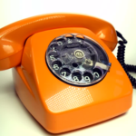 An image of an orange telephone on a white surface