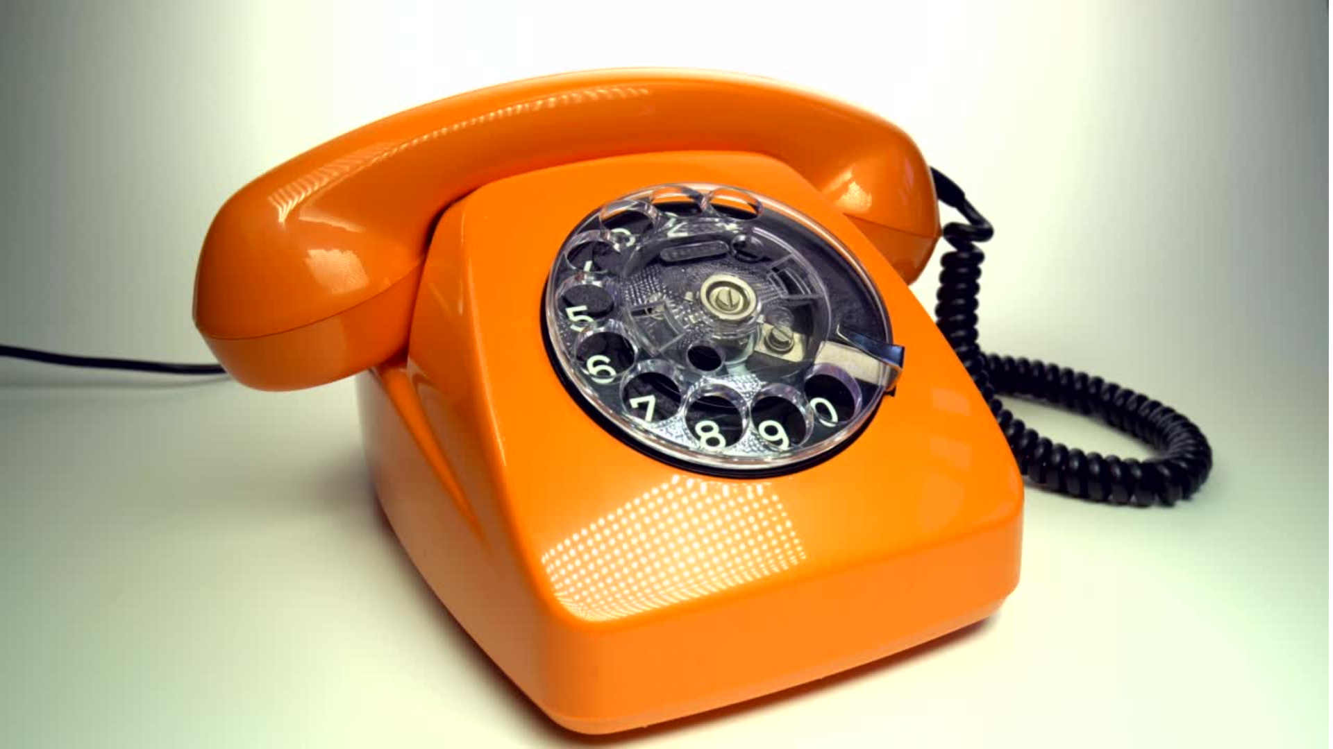 An image of an orange telephone on a white surface