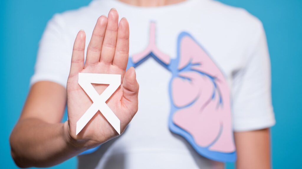 Image of someone in a white t-shirt displaying a graphic of the inside of a lung. The person is holding up a white ribbon to raise awareness of lung cancer.