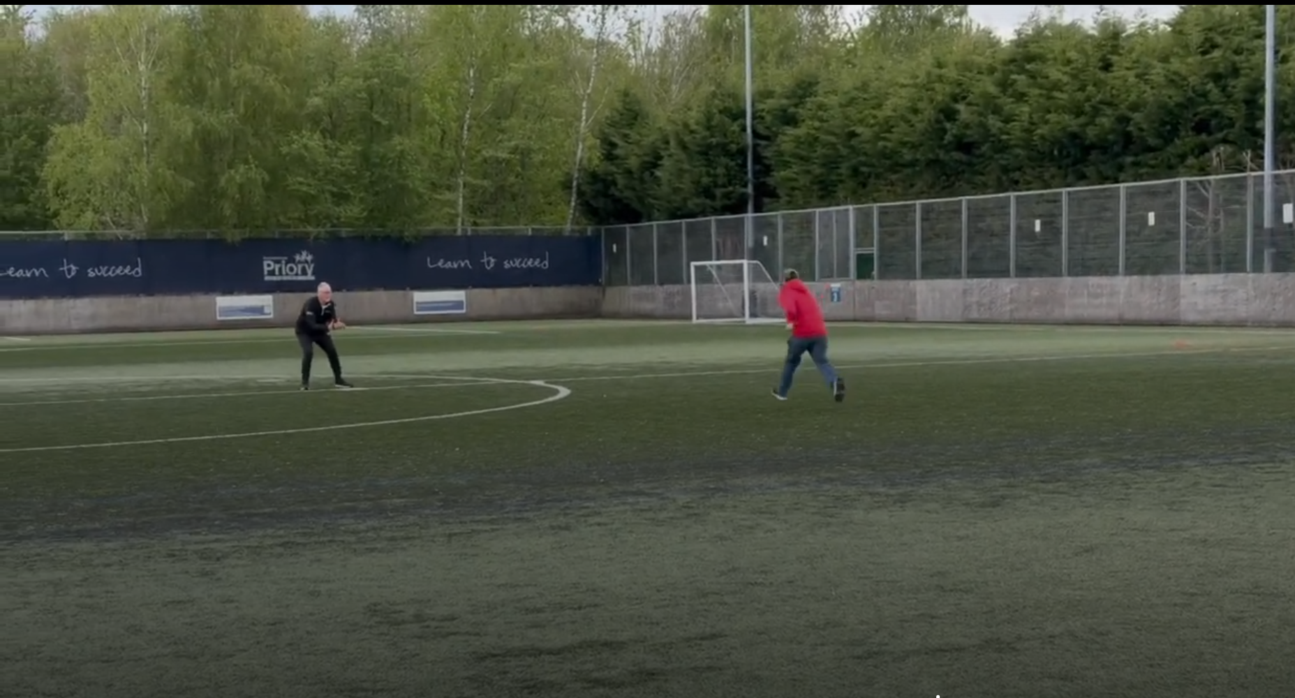 Image of someone in a red jacket running to a base in blind baseball.
