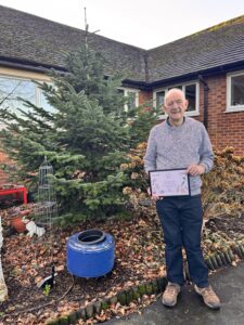 James Towersy holding an RHS Britain in Bloom Outstanding Level 5 award in the Galloways garden.