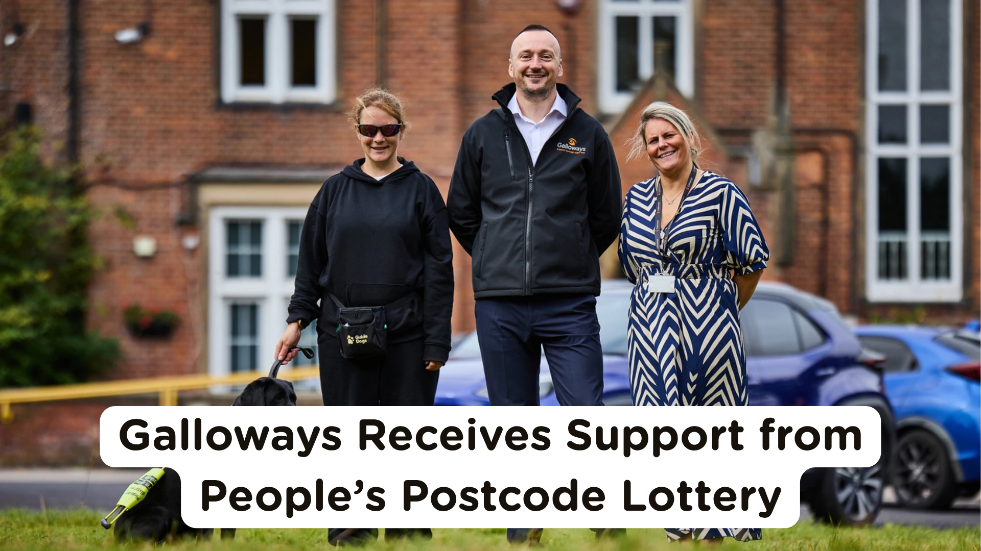 Loaraine stands with her guide dog Gigi alongside CEO Iain Pearson and Kelly Love outside Howick House at Galloways, smiling in front of a brick building. A car is parked behind them. Overlaid text reads: “Galloways Receives Support from People’s Postcode Lottery.”